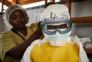 Una trabajadora sanitaria se coloca el equipo de protección individual (EPI) antes de entrar en un centro de tratamiento del ébola