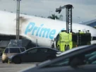 Avión varado en medio de la carretera, con una gran llamarada de humo a sus espaldas.